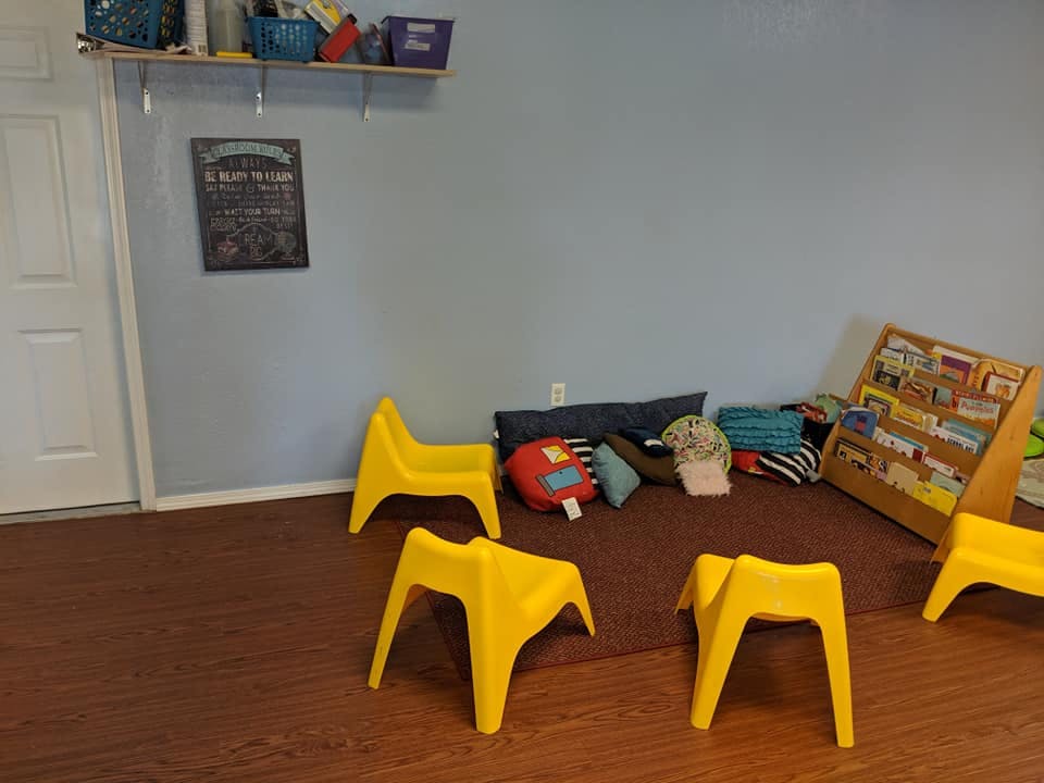 Children's play area with yellow chairs, pillows, and a book display