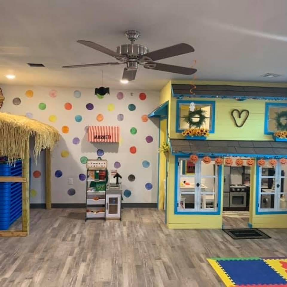 Playroom with a yellow playhouse and a market stand against a polka dot wall