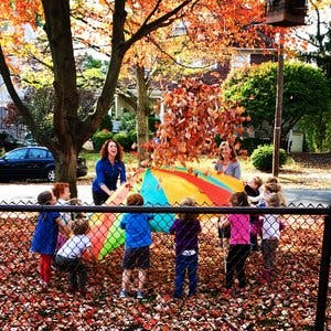 Adults and children playing with a parachute and leaves