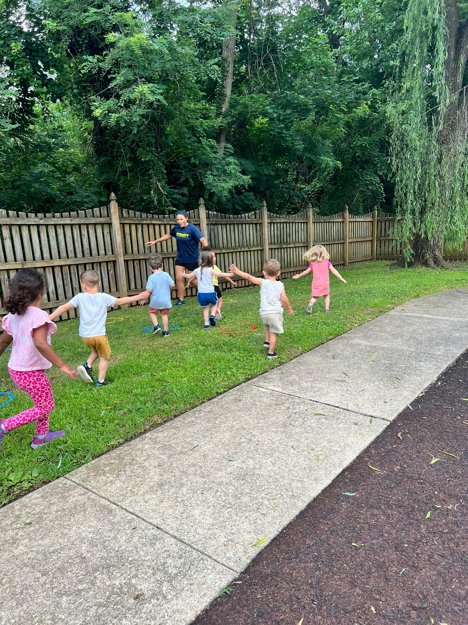 Adult and several children playing a game in a grassy area
