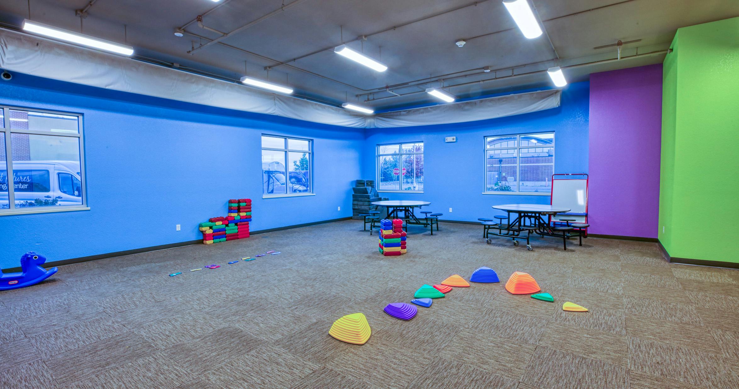 Childcare playroom with colorful walls, tables, and play equipment