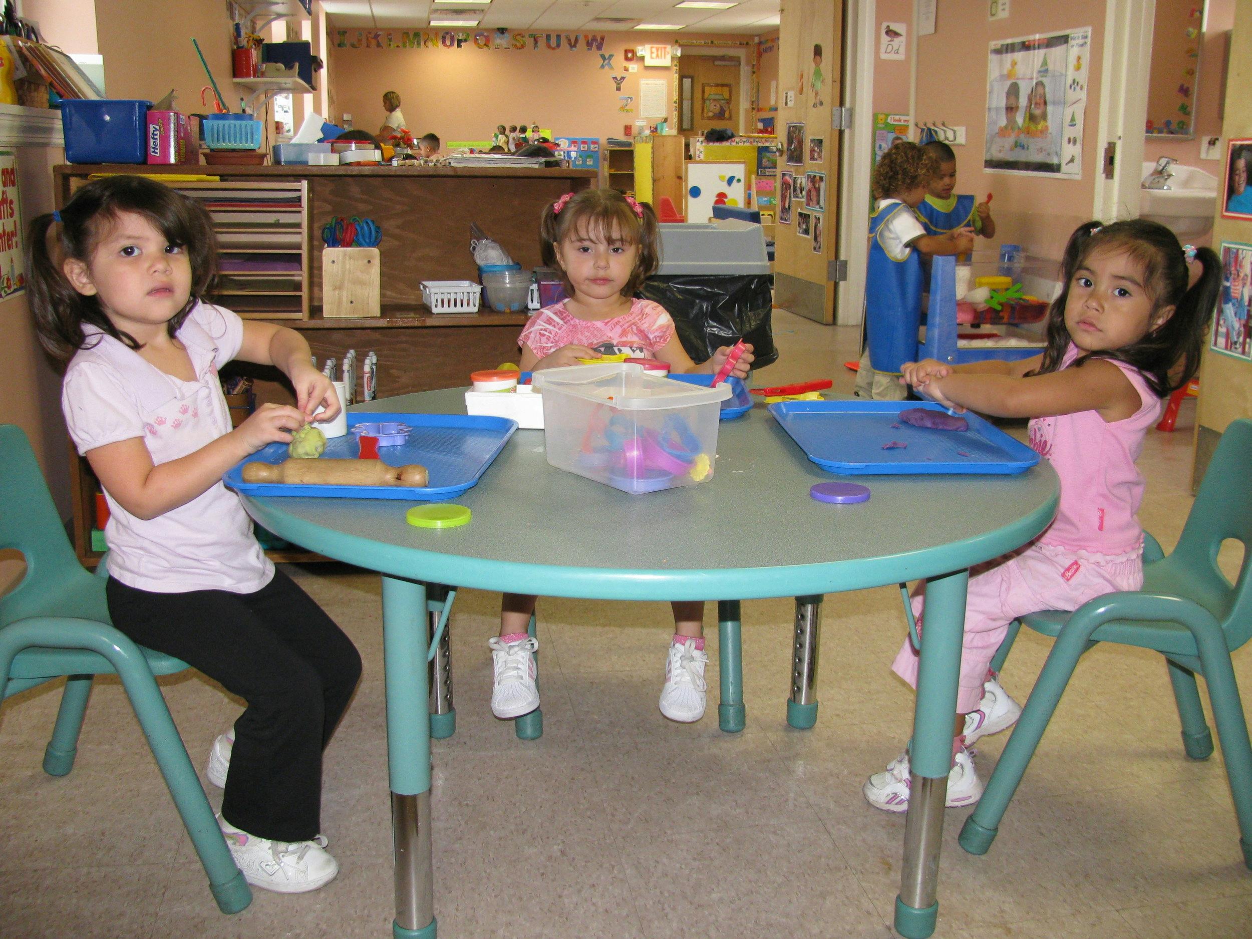 Three children sitting at a table in a classroom