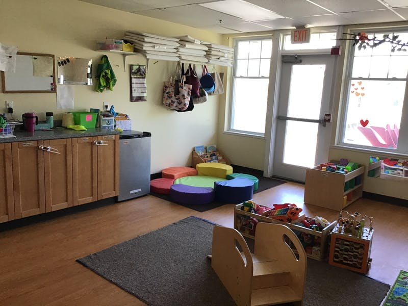 Classroom with cabinets, colorful floor cushions, and child-sized furniture
