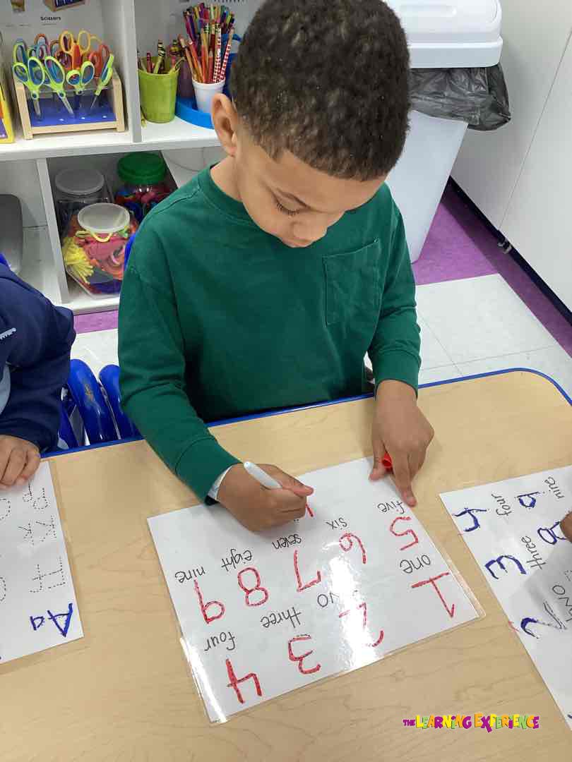 Child writing numbers 1-9 on a worksheet