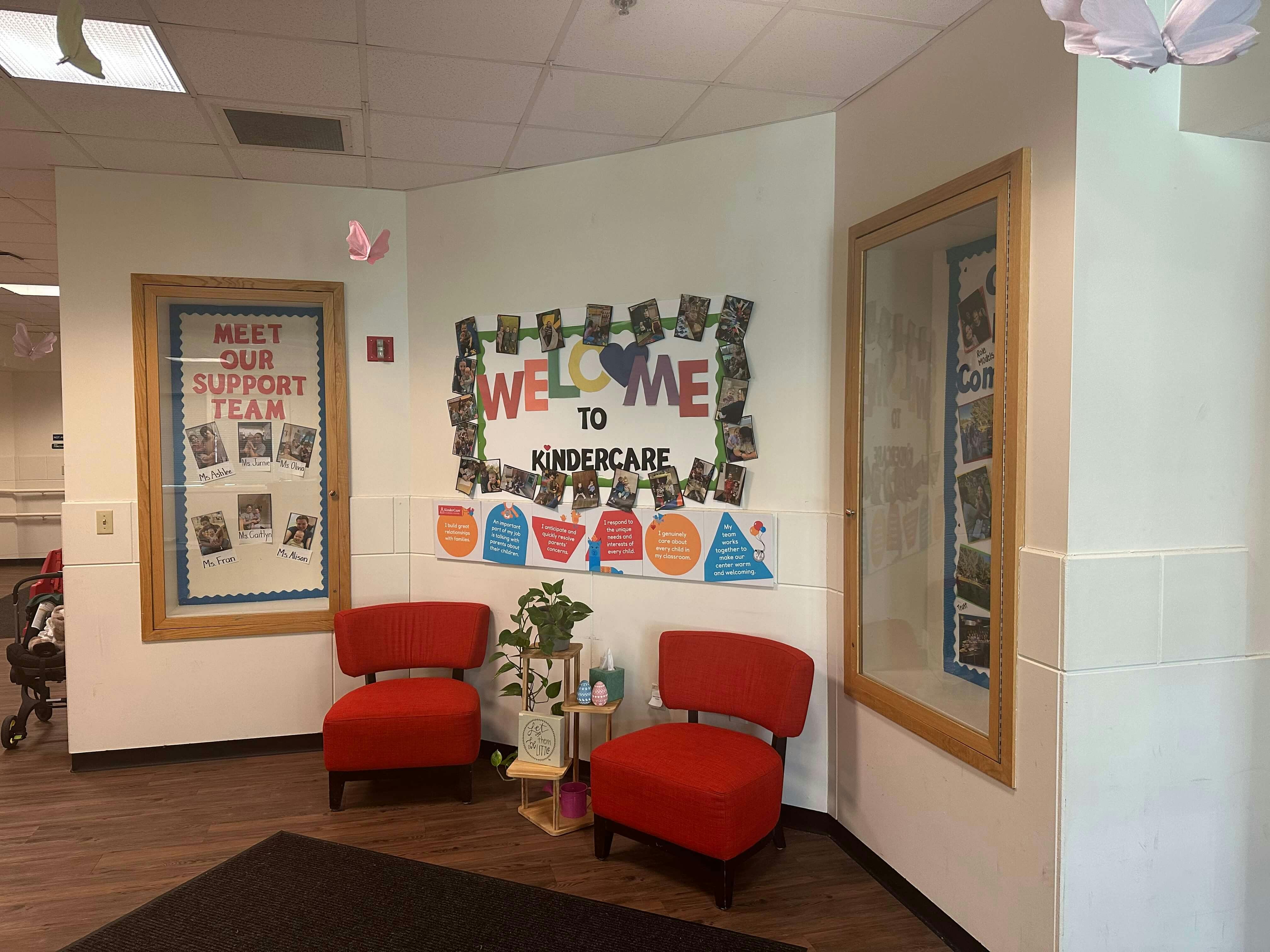 Lobby area with two red chairs and bulletin boards with text including 'Welcome to Kindercare'