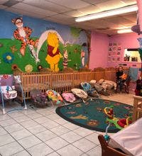 Nursery room with cribs, infant seats, and a Winnie the Pooh mural