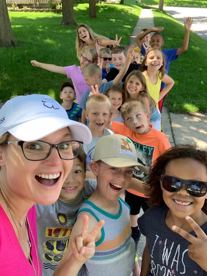 Person taking a selfie with a group of children behind them