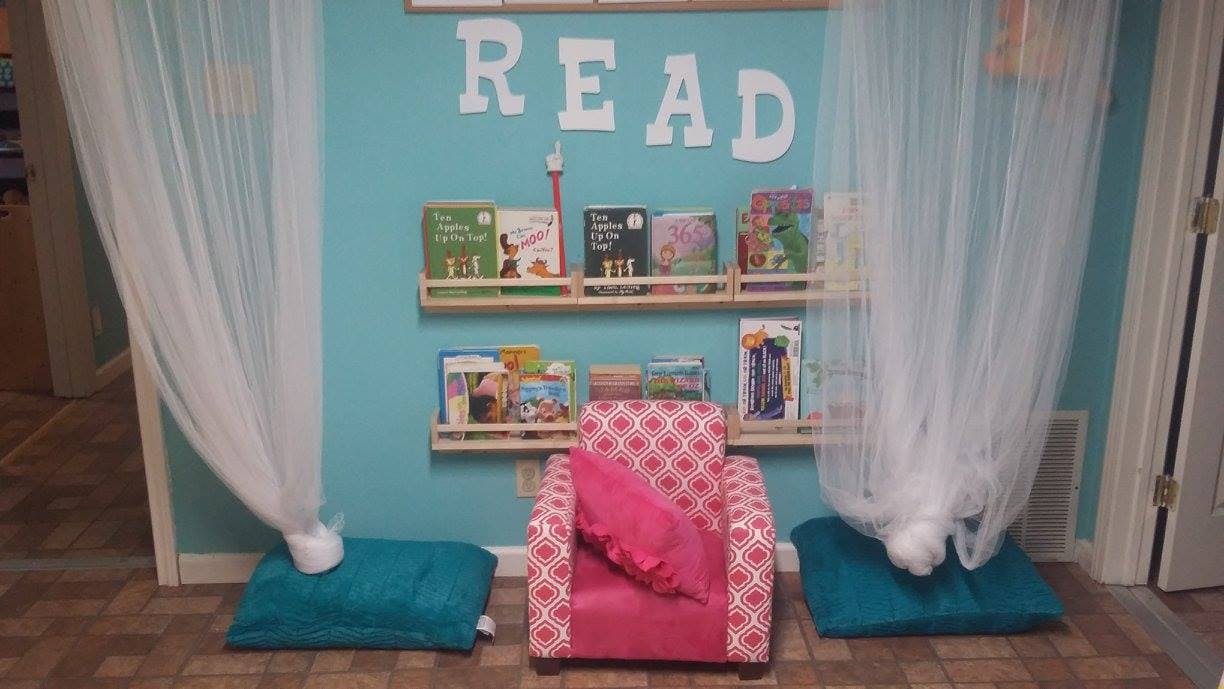 Reading nook with a pink chair, bookshelves, and the word READ on the wall