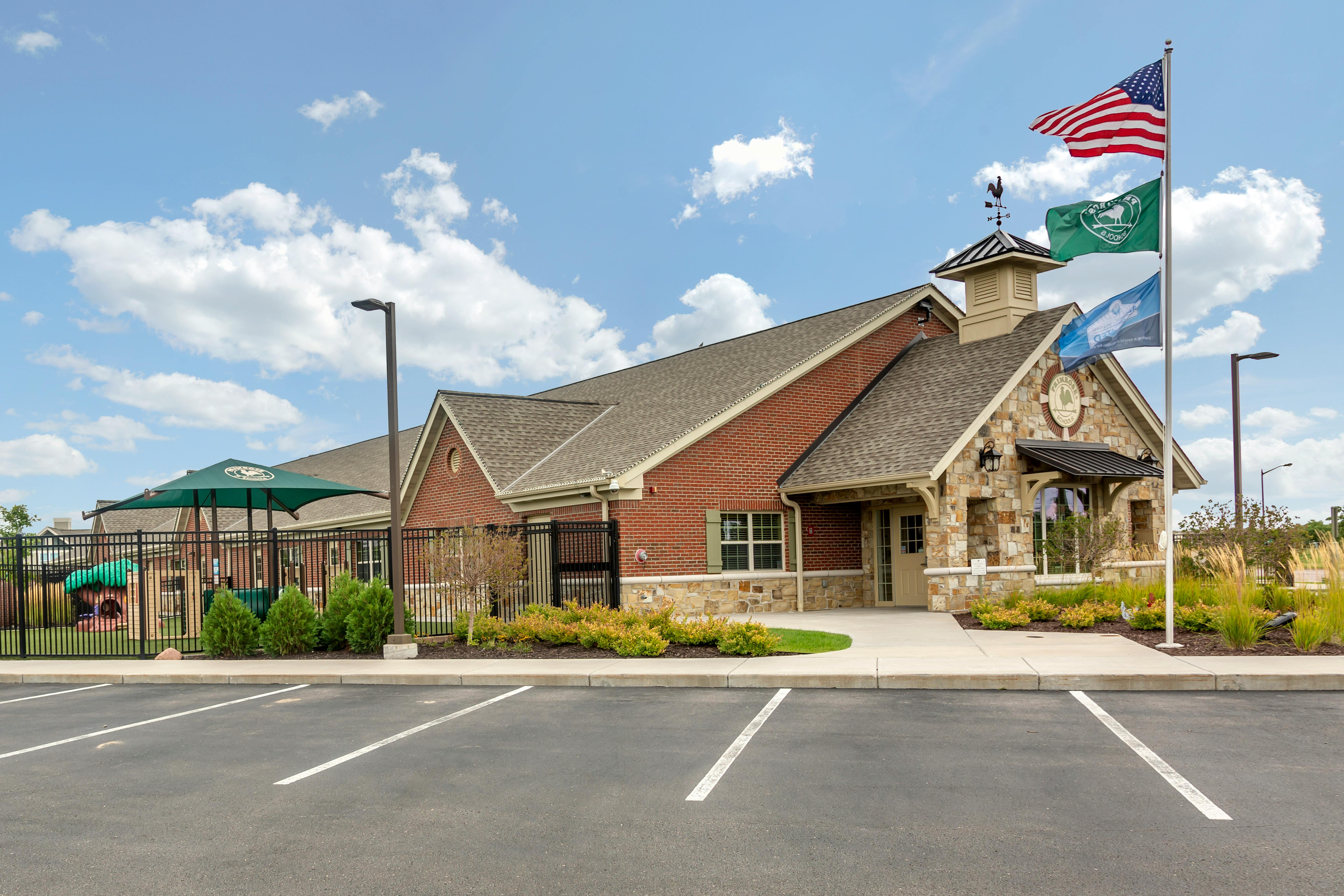 Childcare facility with red brick and stone facade, playground, and American flag