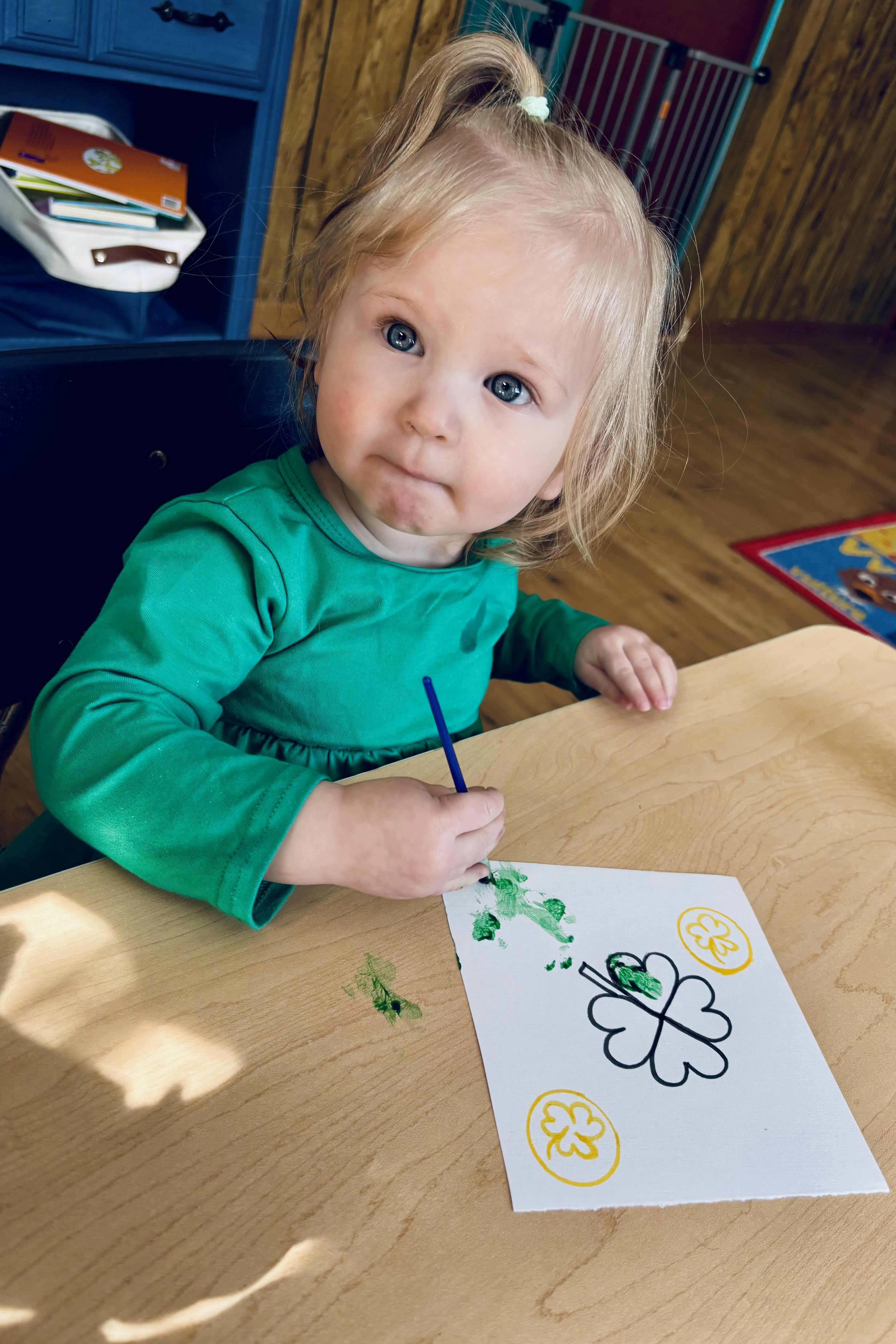 Child painting a shamrock on a piece of paper