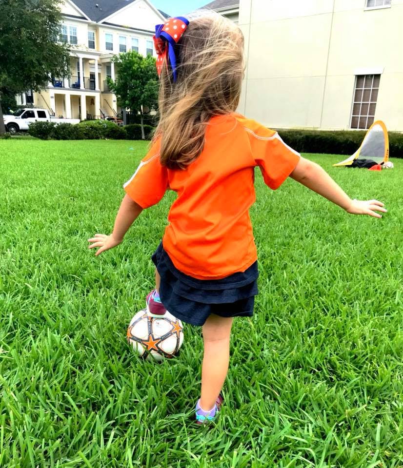 Child playing soccer in a grassy area