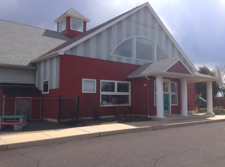 Red and gray building with a large arched window and a covered entrance