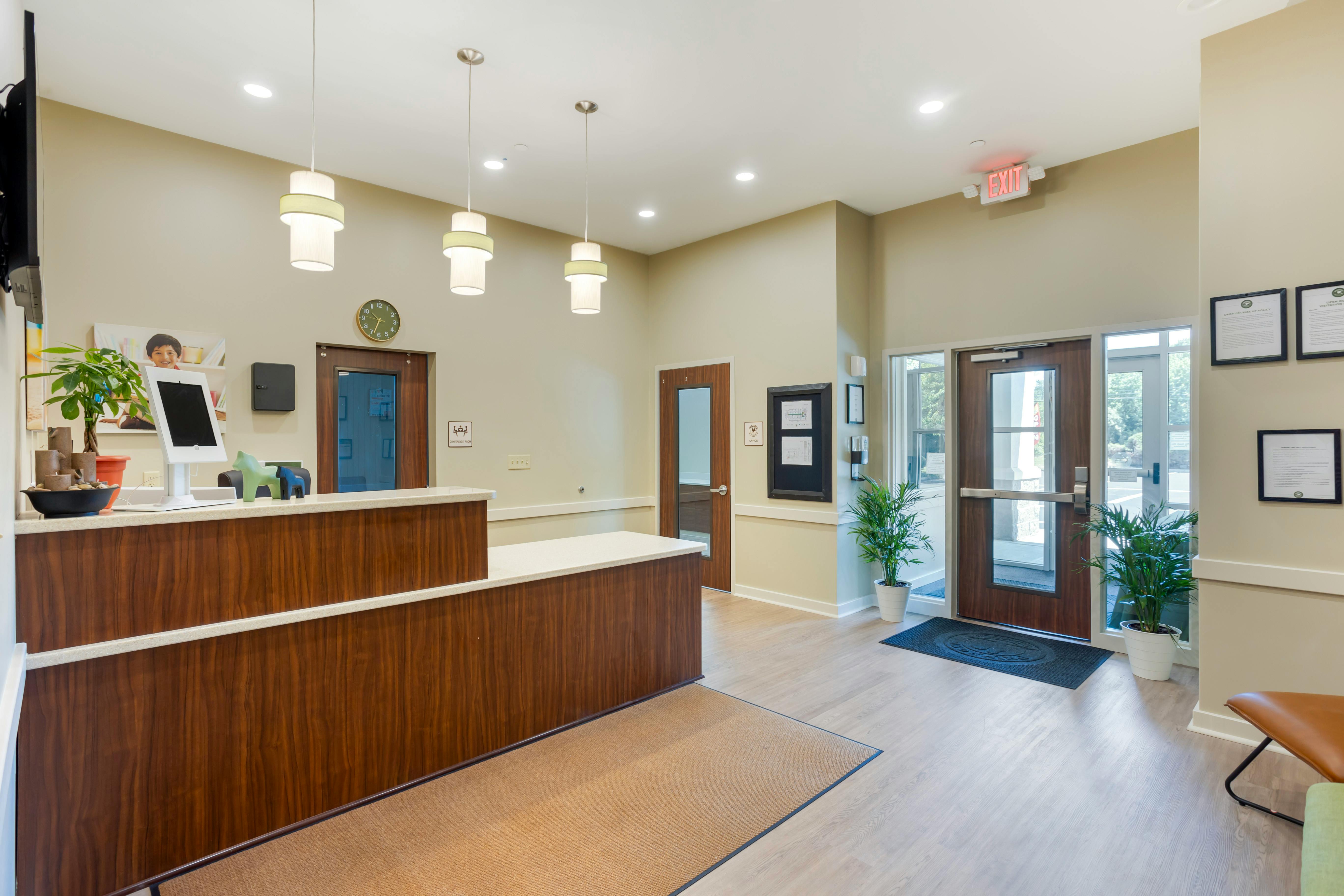 An empty reception area with a wooden desk and exit doors