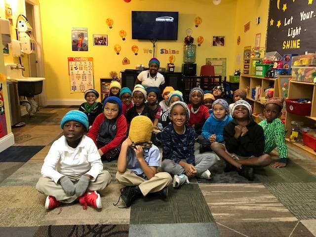 Group of children and adults sitting on the floor in a classroom