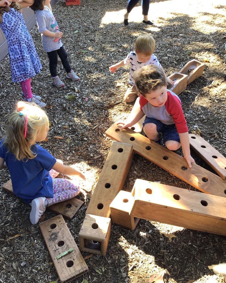 Children playing with wooden blocks outdoors