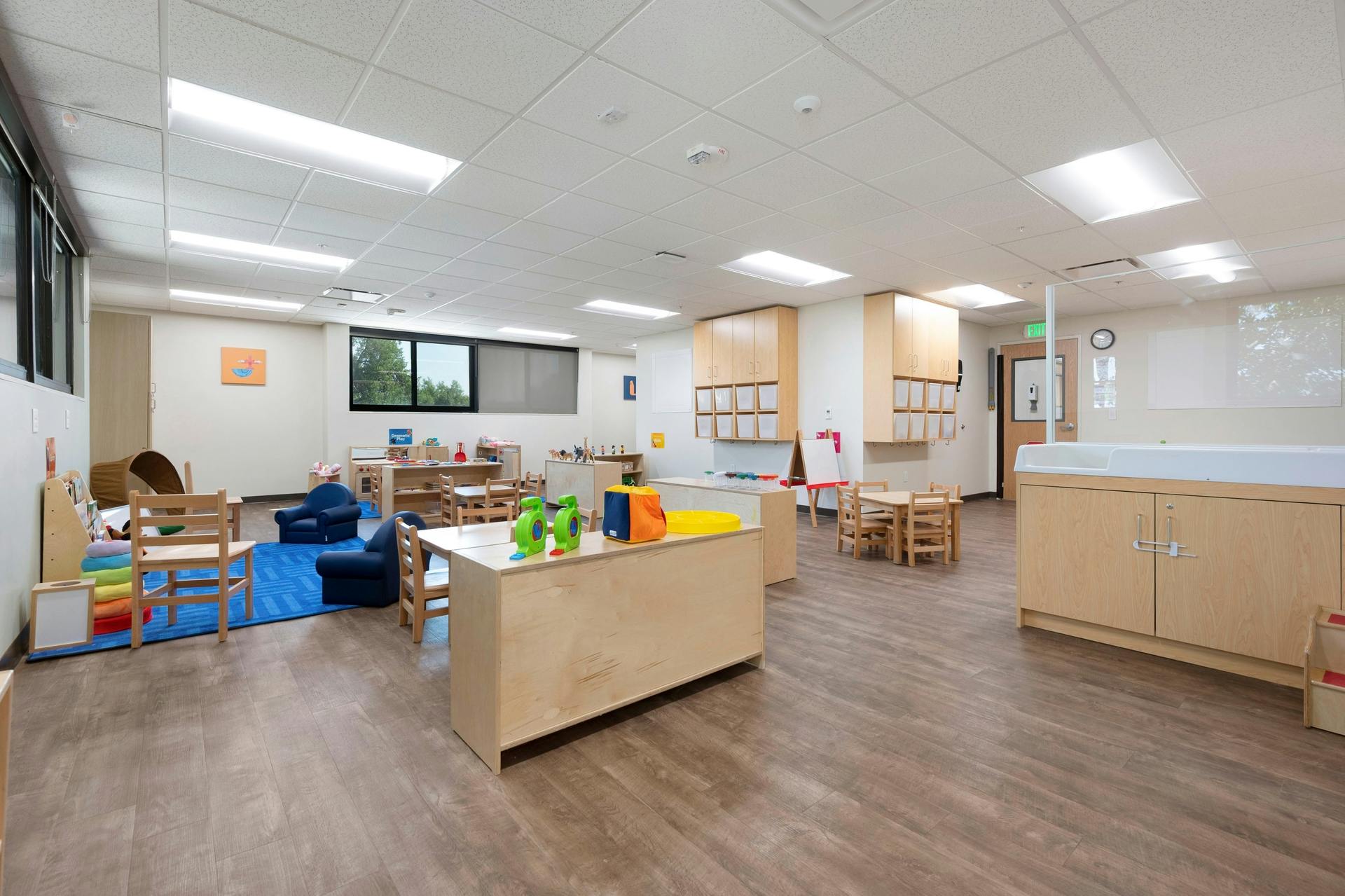 Empty classroom with small tables, chairs, and play areas