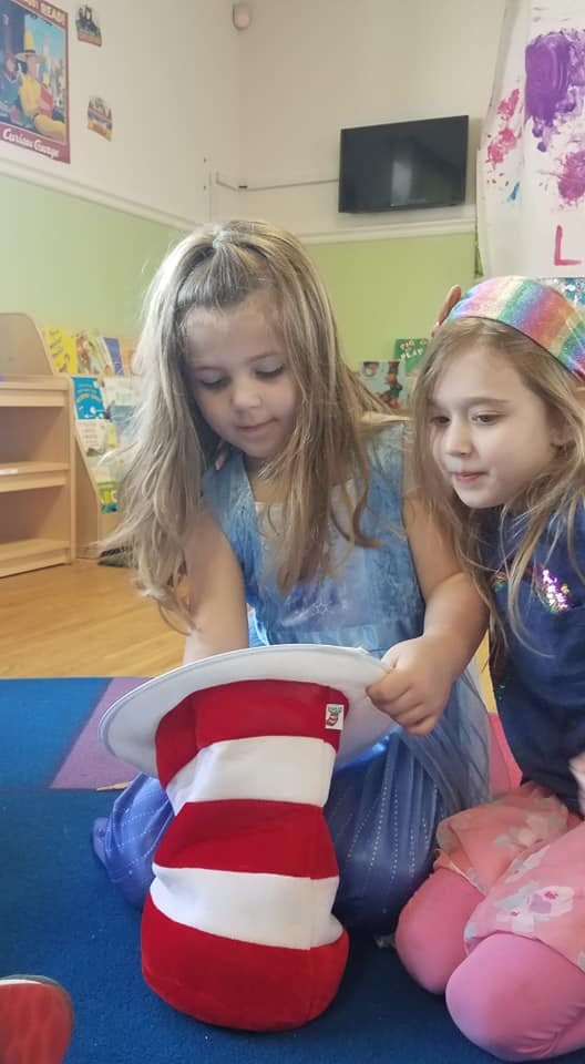 Two children looking at a red and white striped hat