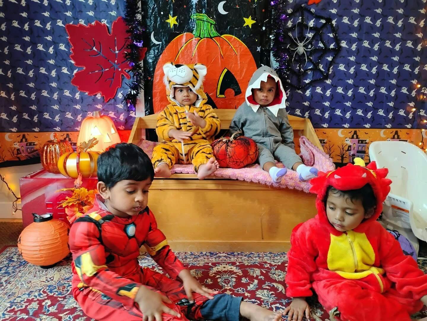 Three children in Halloween costumes with a pumpkin decoration