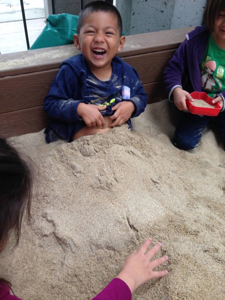 Child laughing in a sandbox