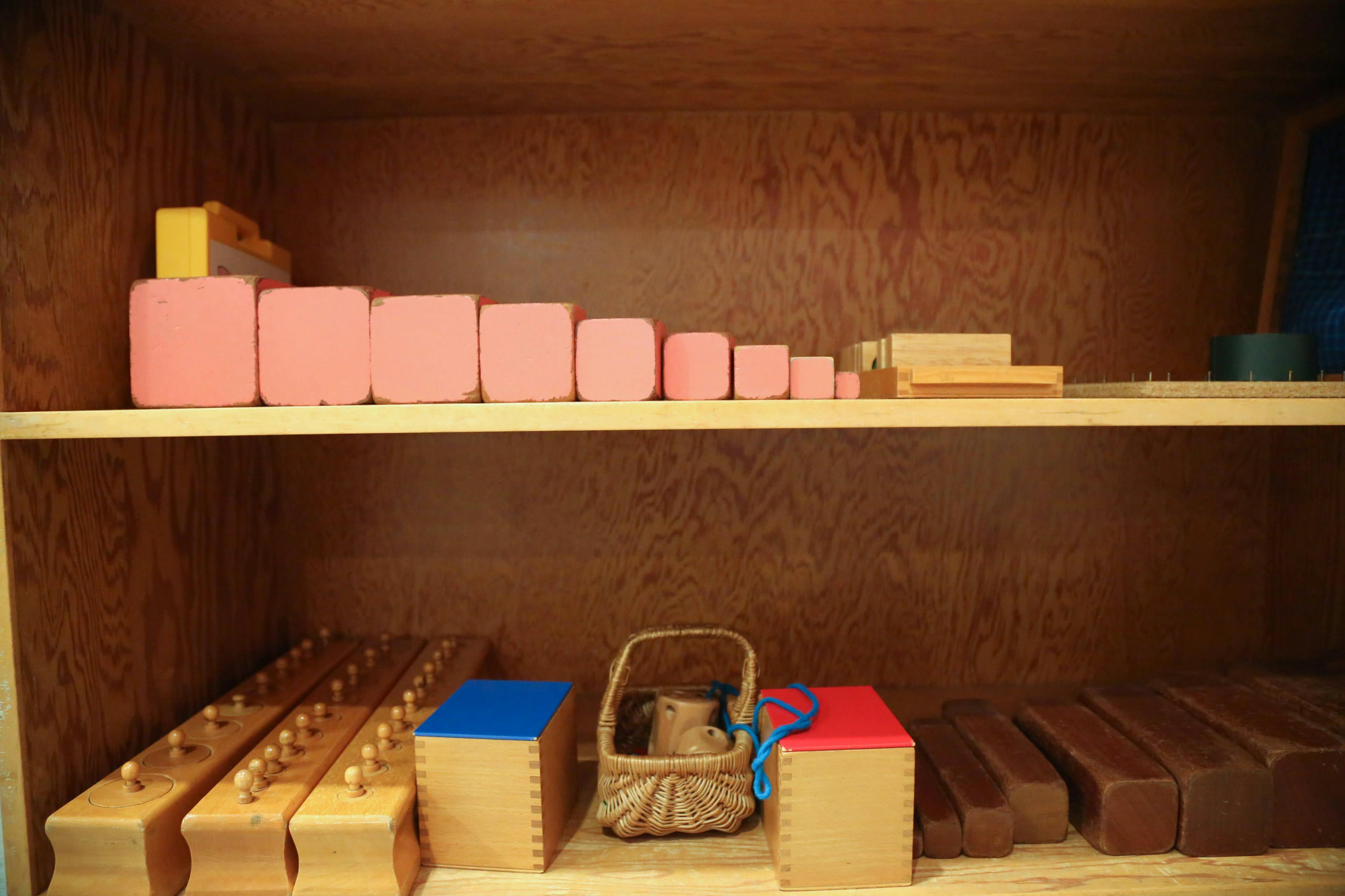Montessori pink tower blocks and other learning materials on shelves