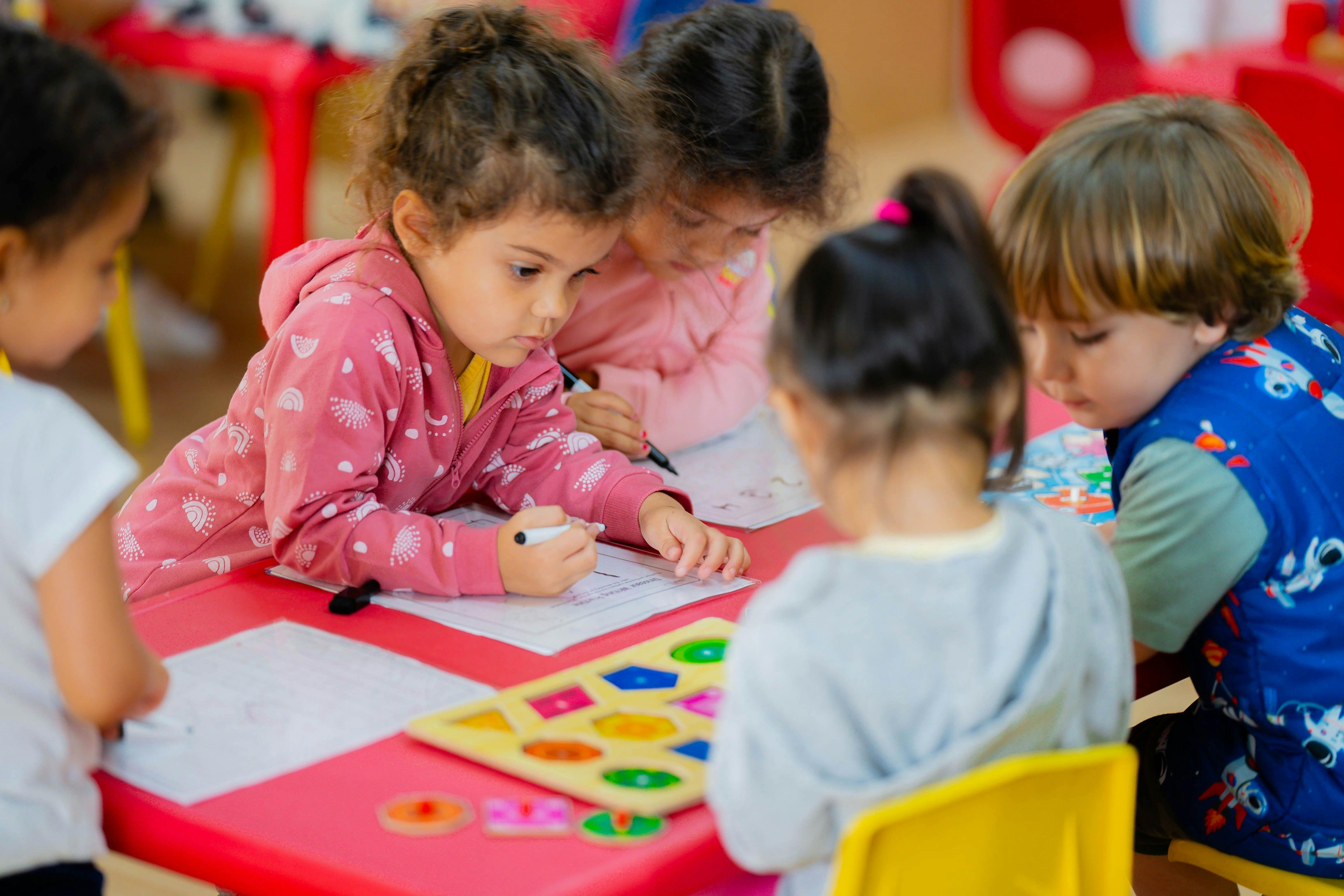 Children at a table drawing and playing with a shape sorter