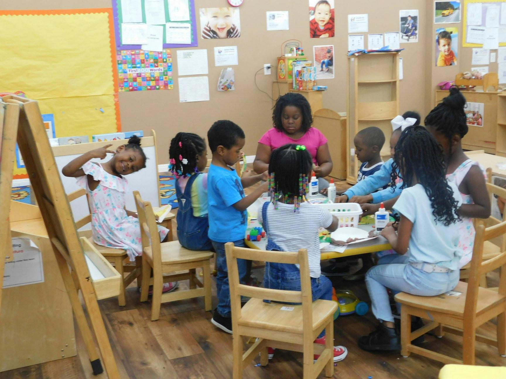 Adult and children gathered around a table in a classroom