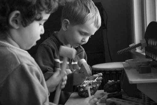 Two children playing with toy hammers and small objects