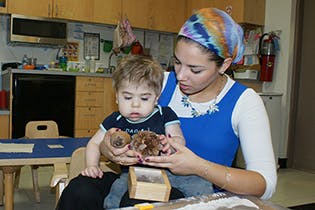 Person holding a child who is looking at a small object