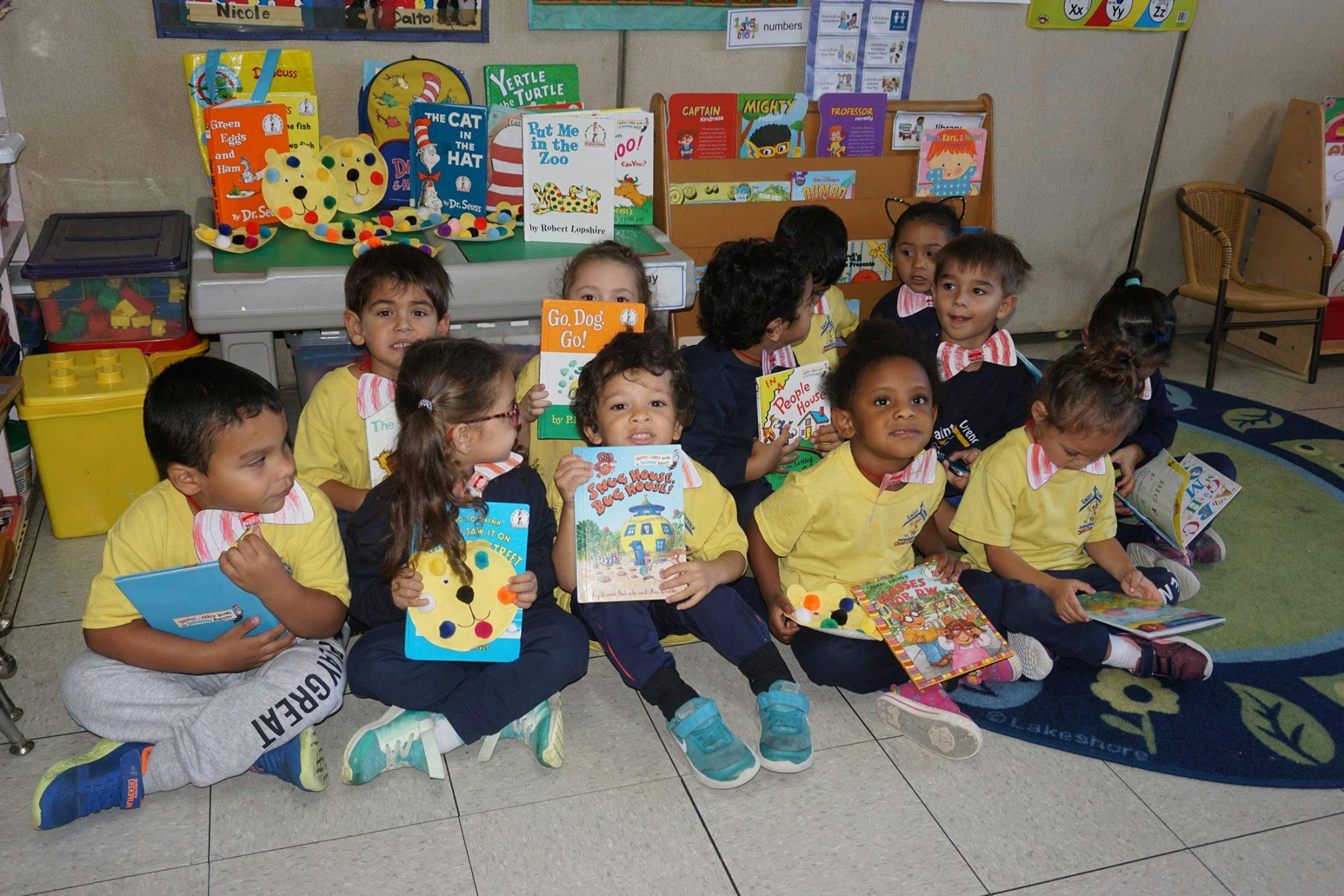 Group of children sitting on the floor holding books in a classroom