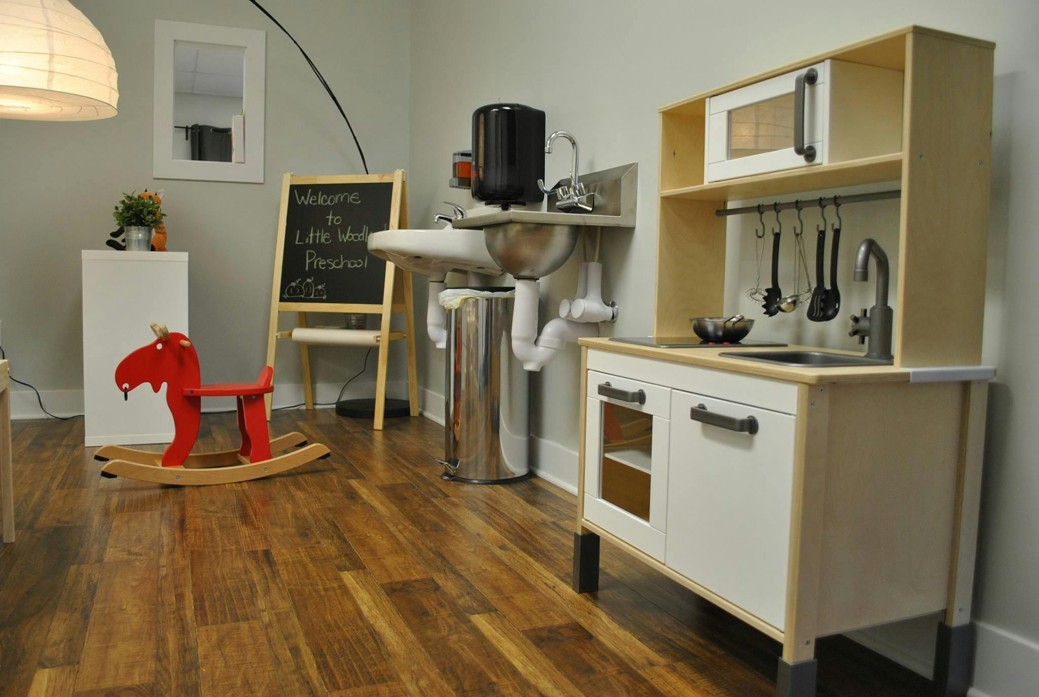 Play kitchen and red rocking horse in a room with a sink