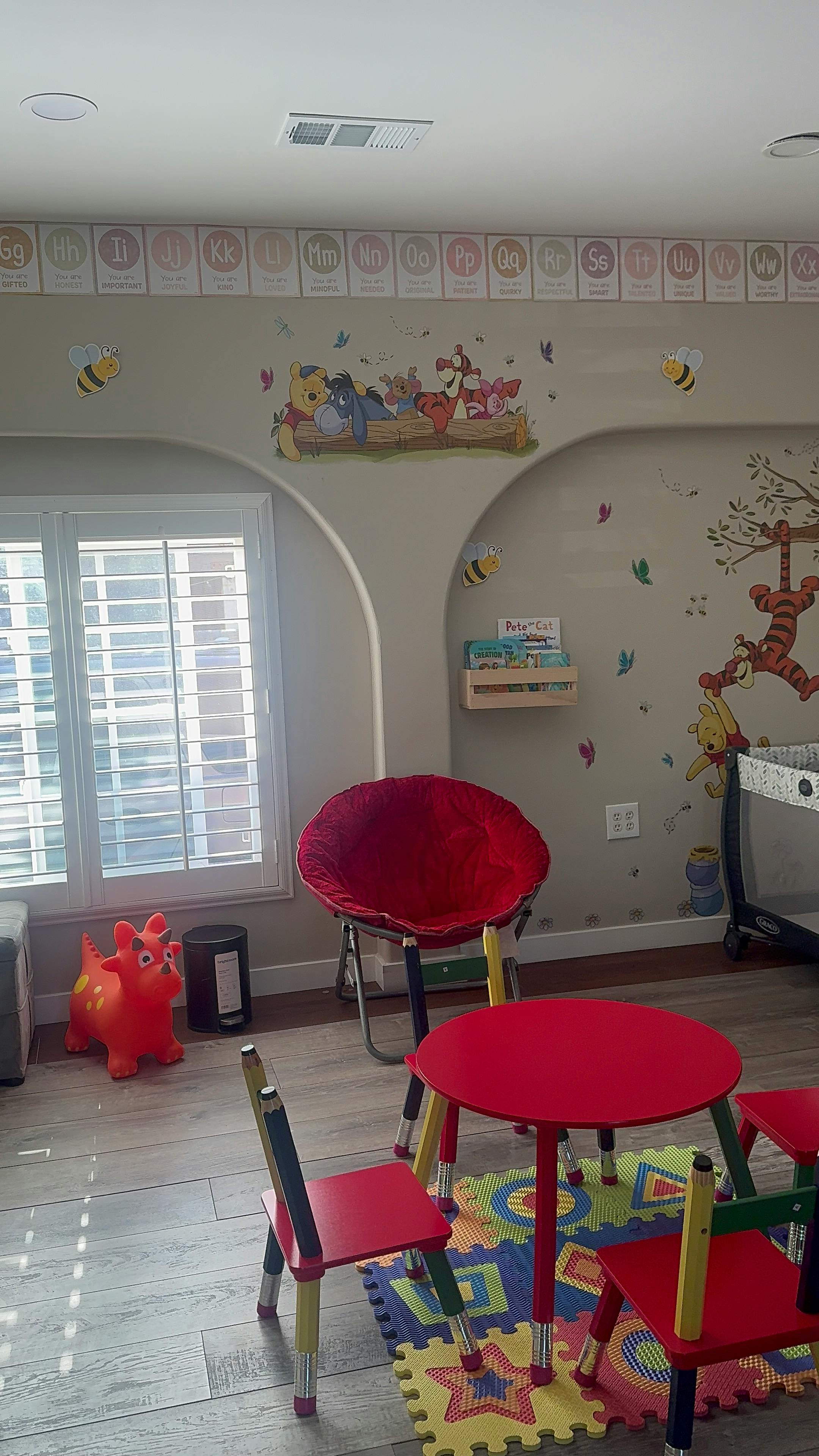 Children's play area with small red table and chairs, and wall decals
