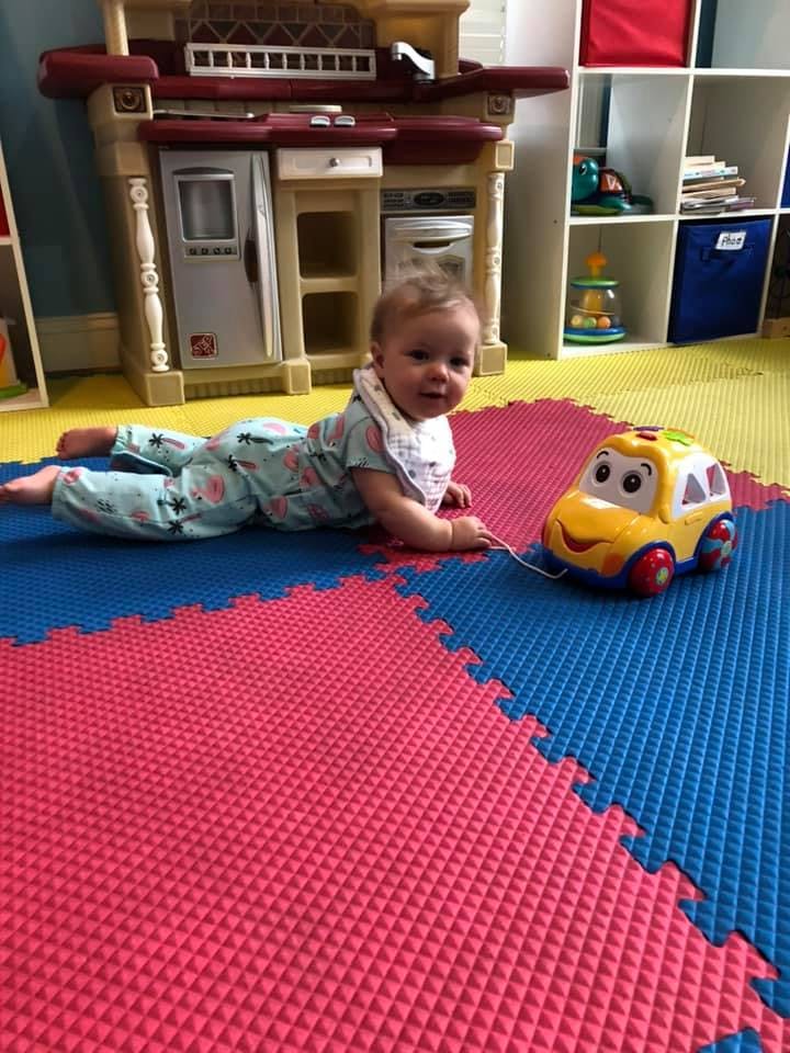 Child on stomach on playmat with toy car