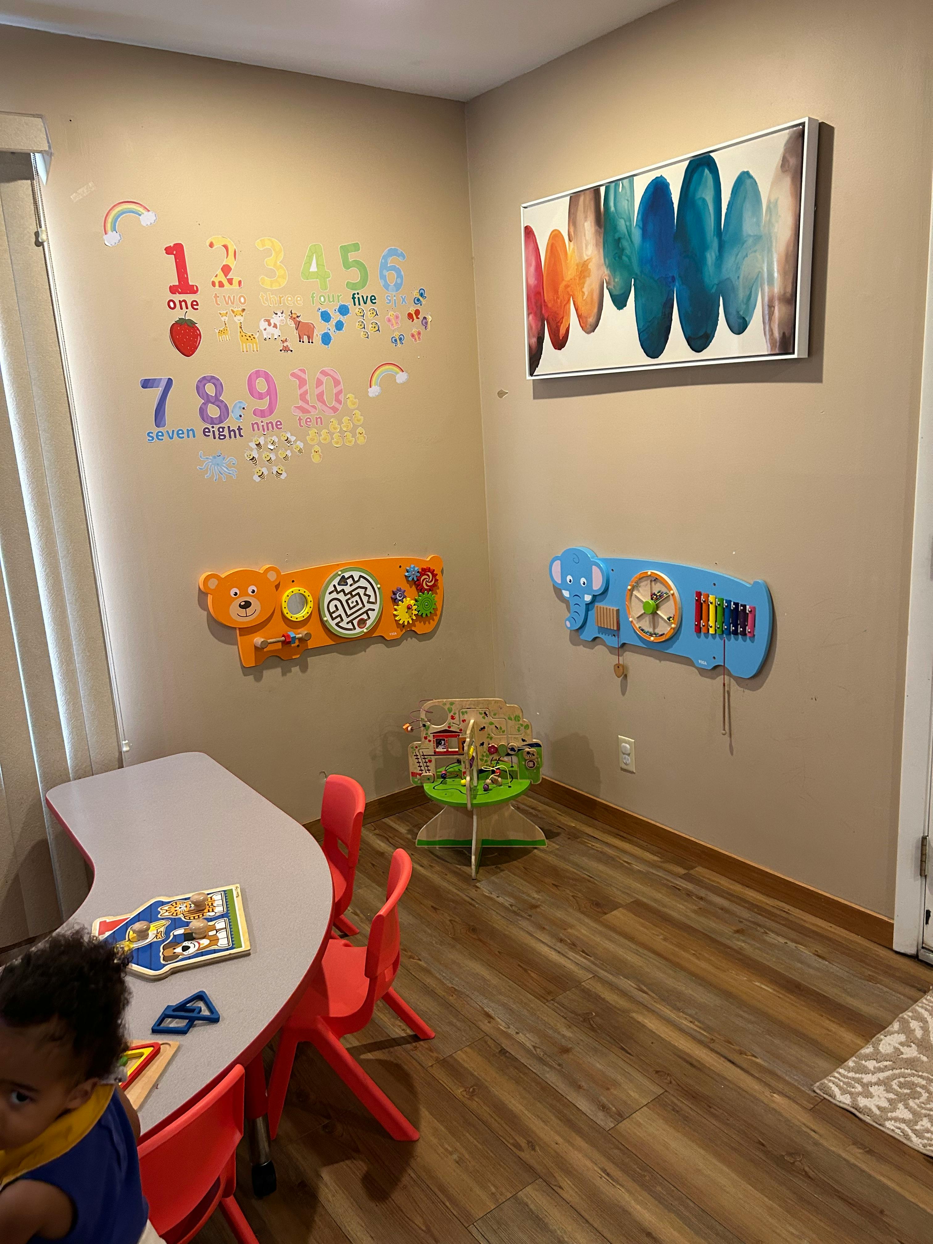 Child sitting at a small table in a room with educational wall decorations