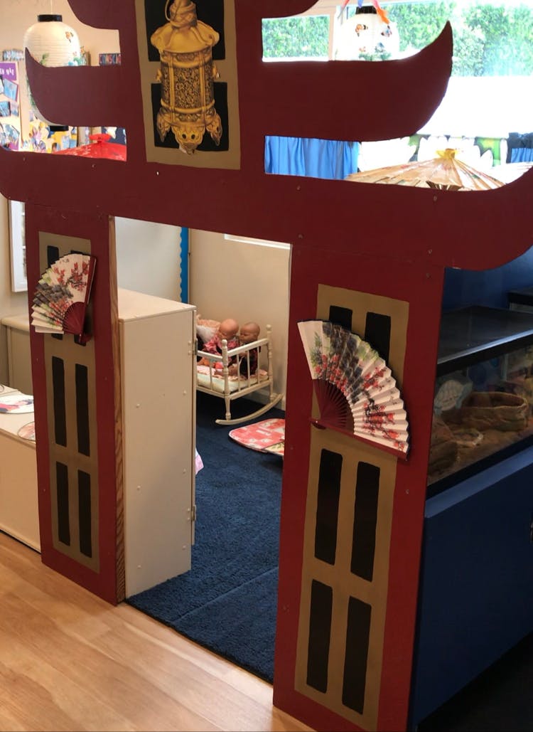 Red decorative archway with fans and a view into a room with a crib