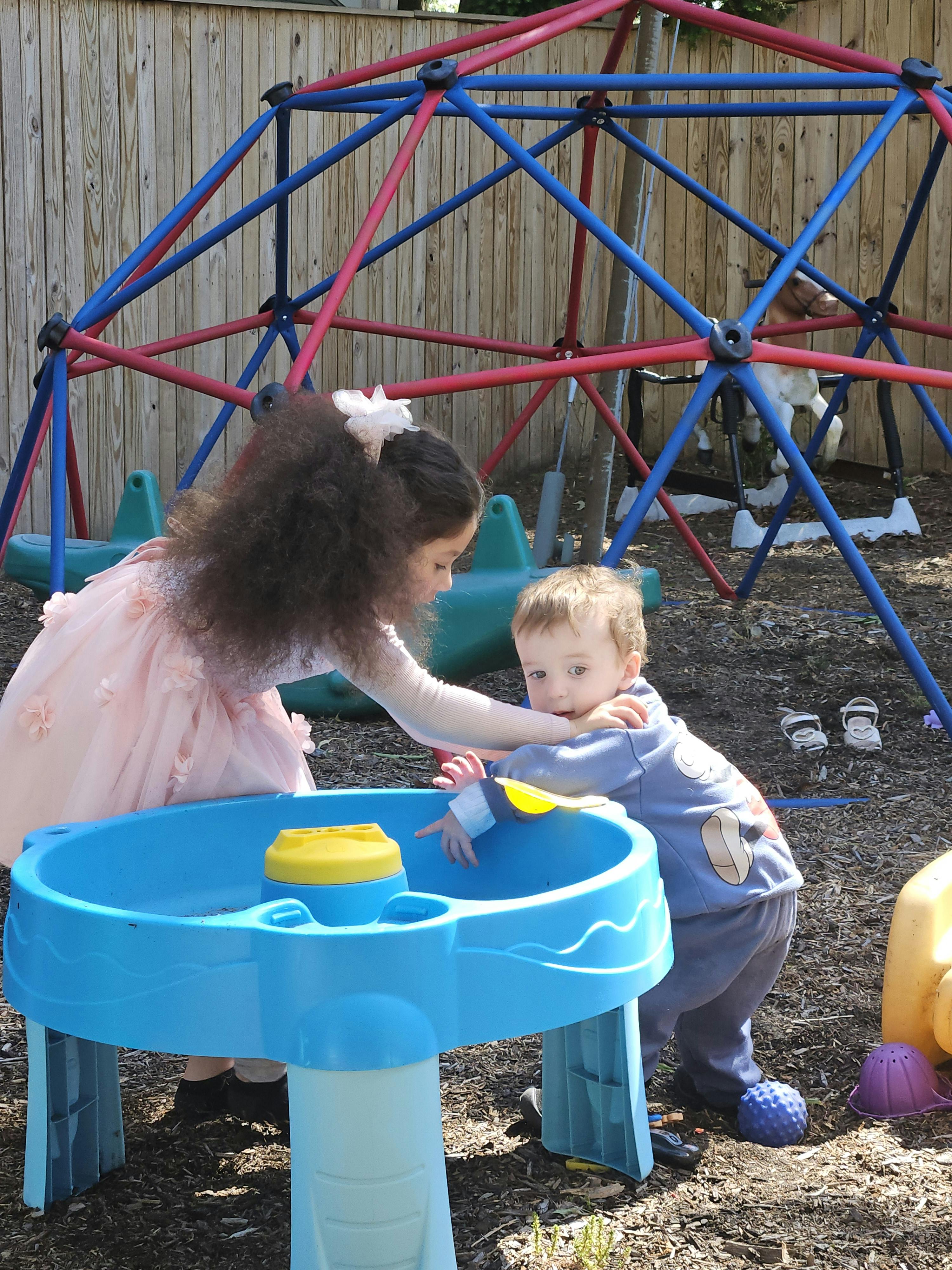 Two children playing at a water table in a playground