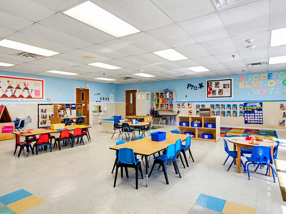 Empty preschool classroom with small tables and chairs