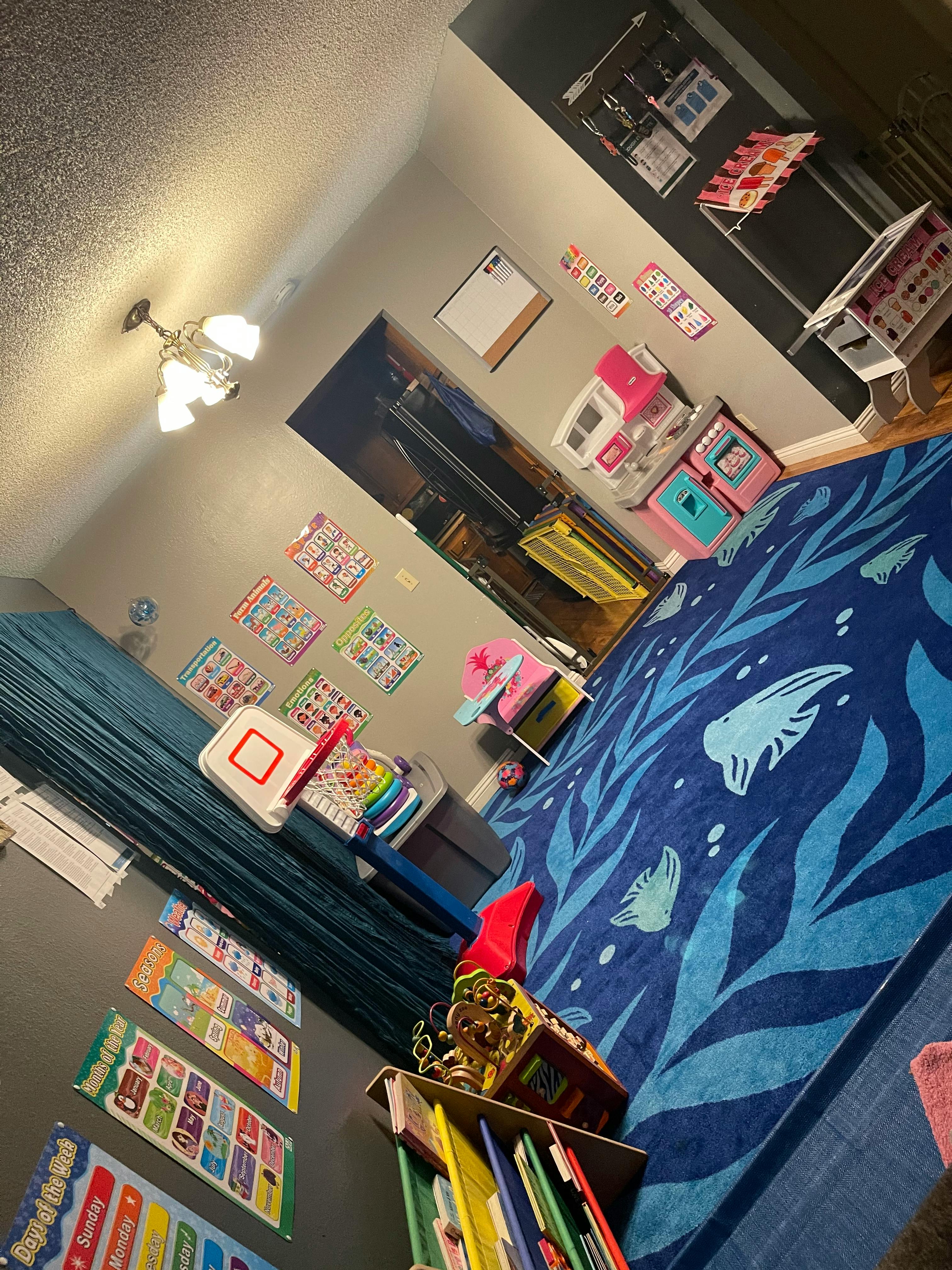 Playroom with a blue rug, toy basketball hoop, and educational posters
