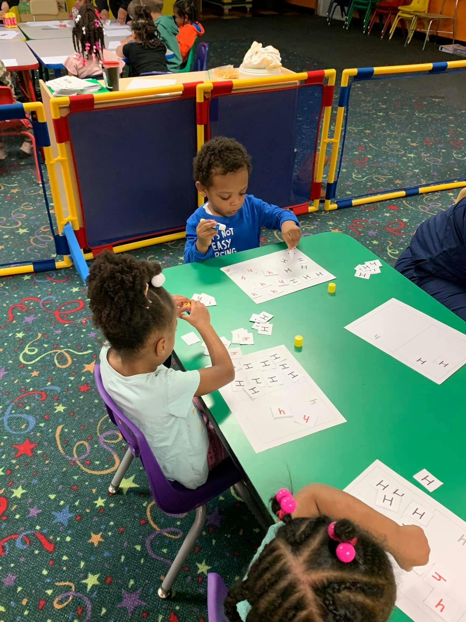 Children at a table working on papers with small objects
