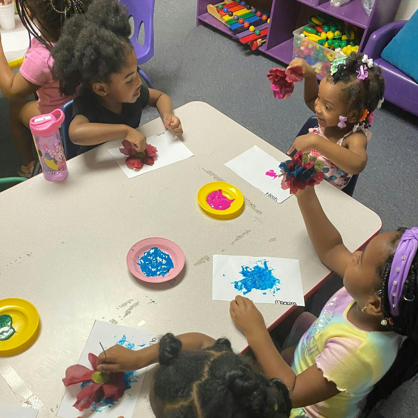 Children painting with pom-poms at a table