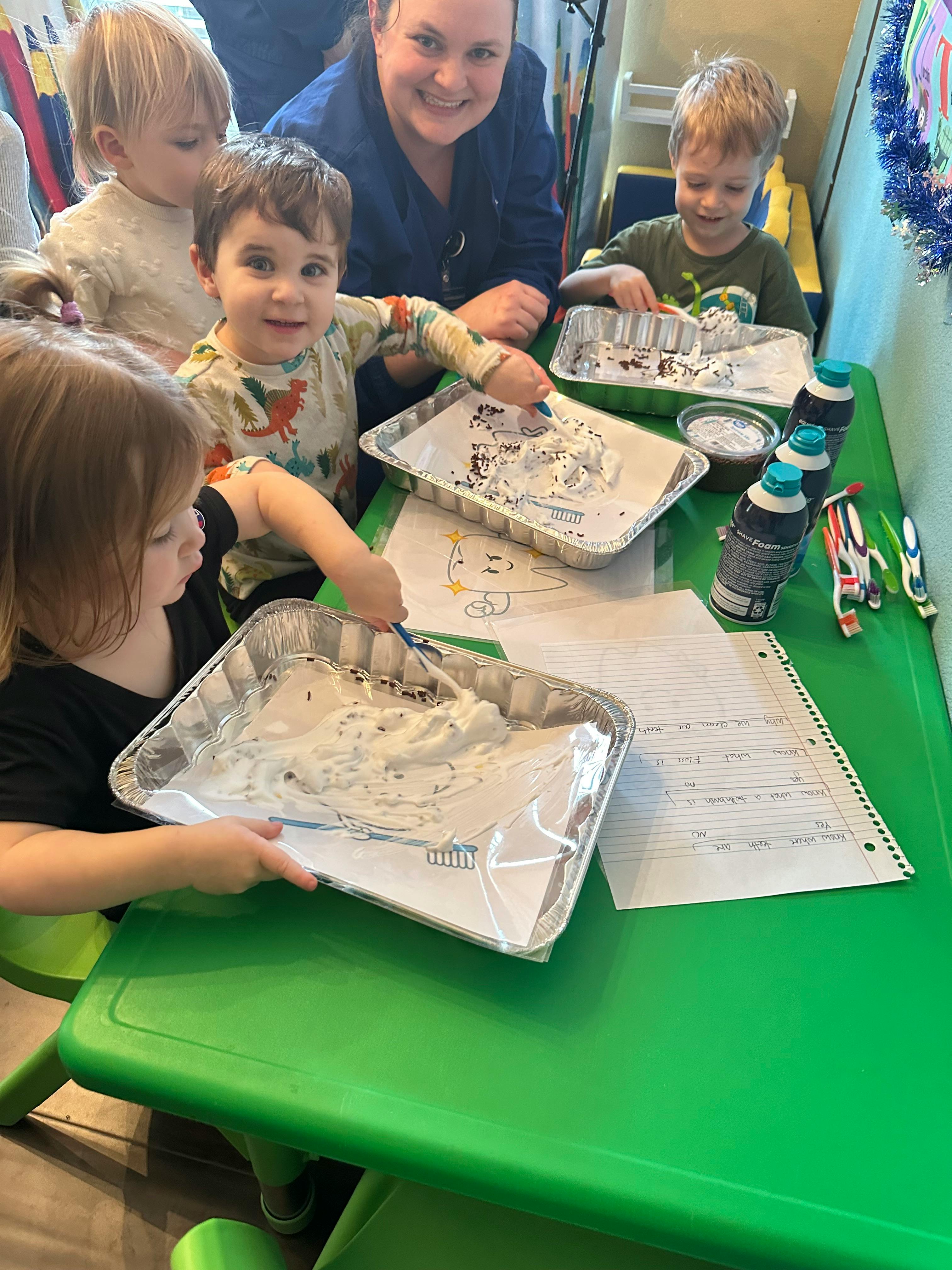 Adult and children at a table doing an art activity with shaving cream