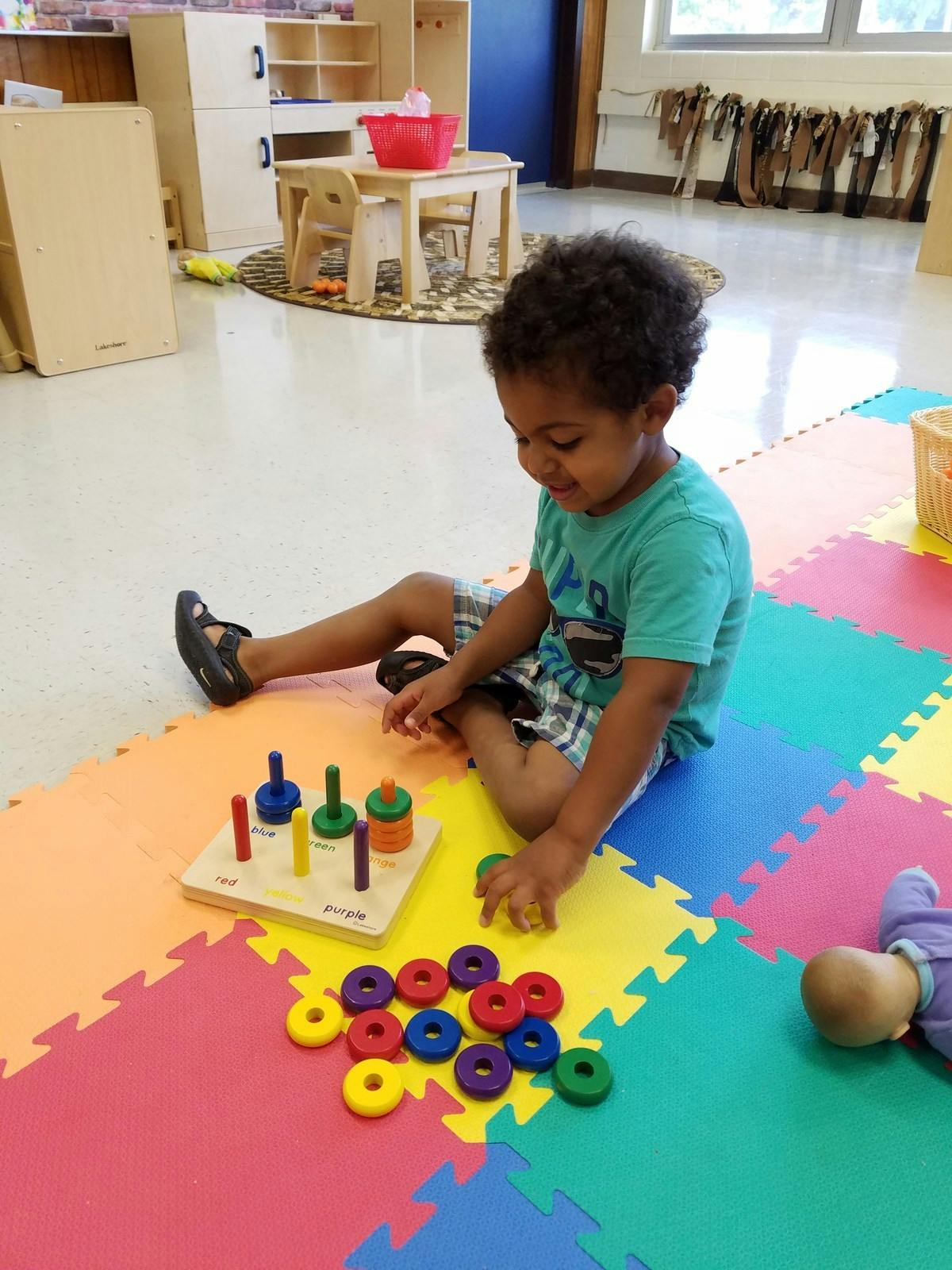 Child sitting on floor playing with a stacking toy