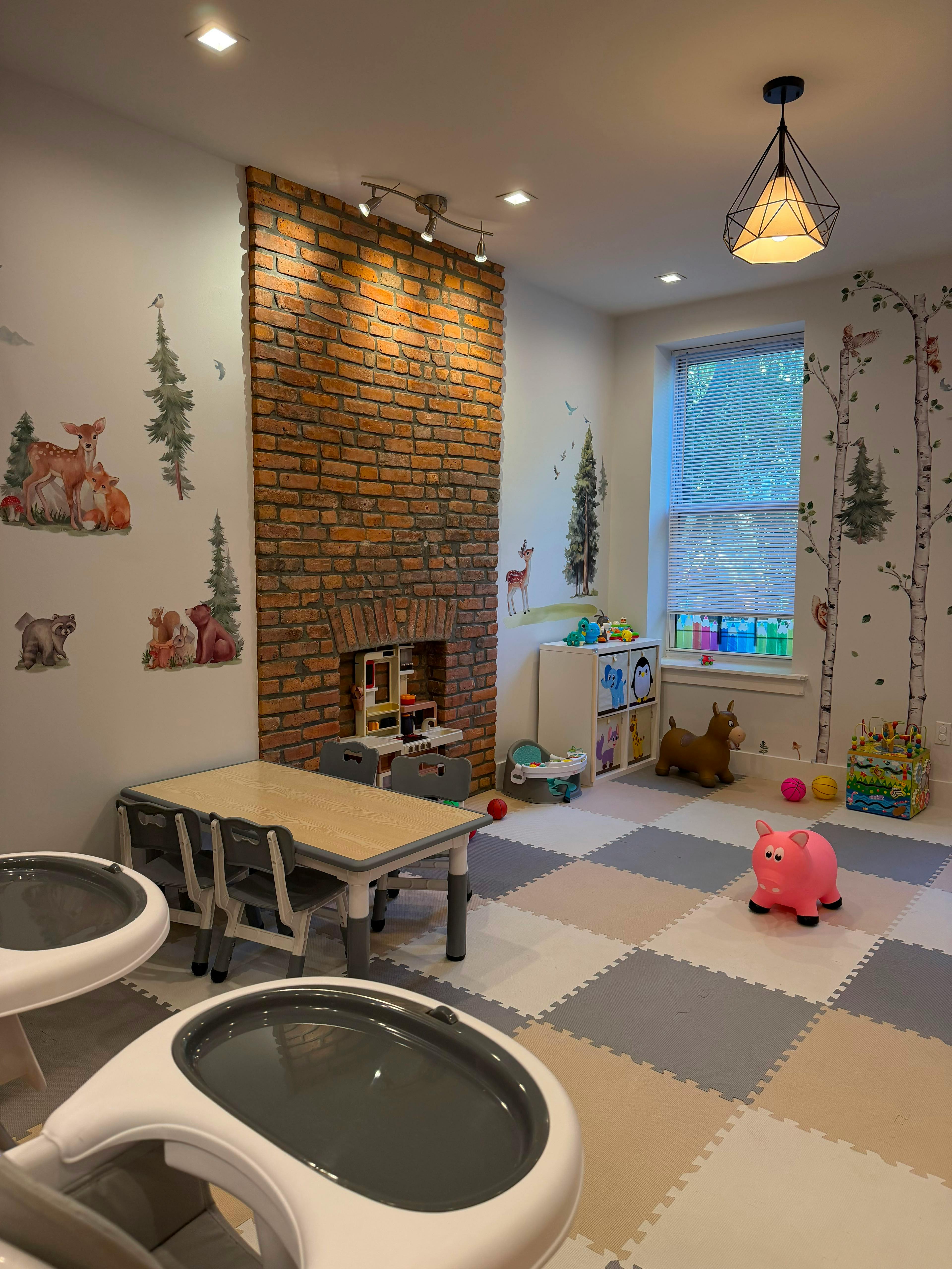 Playroom with a brick fireplace, children's furniture, and forest wall decals