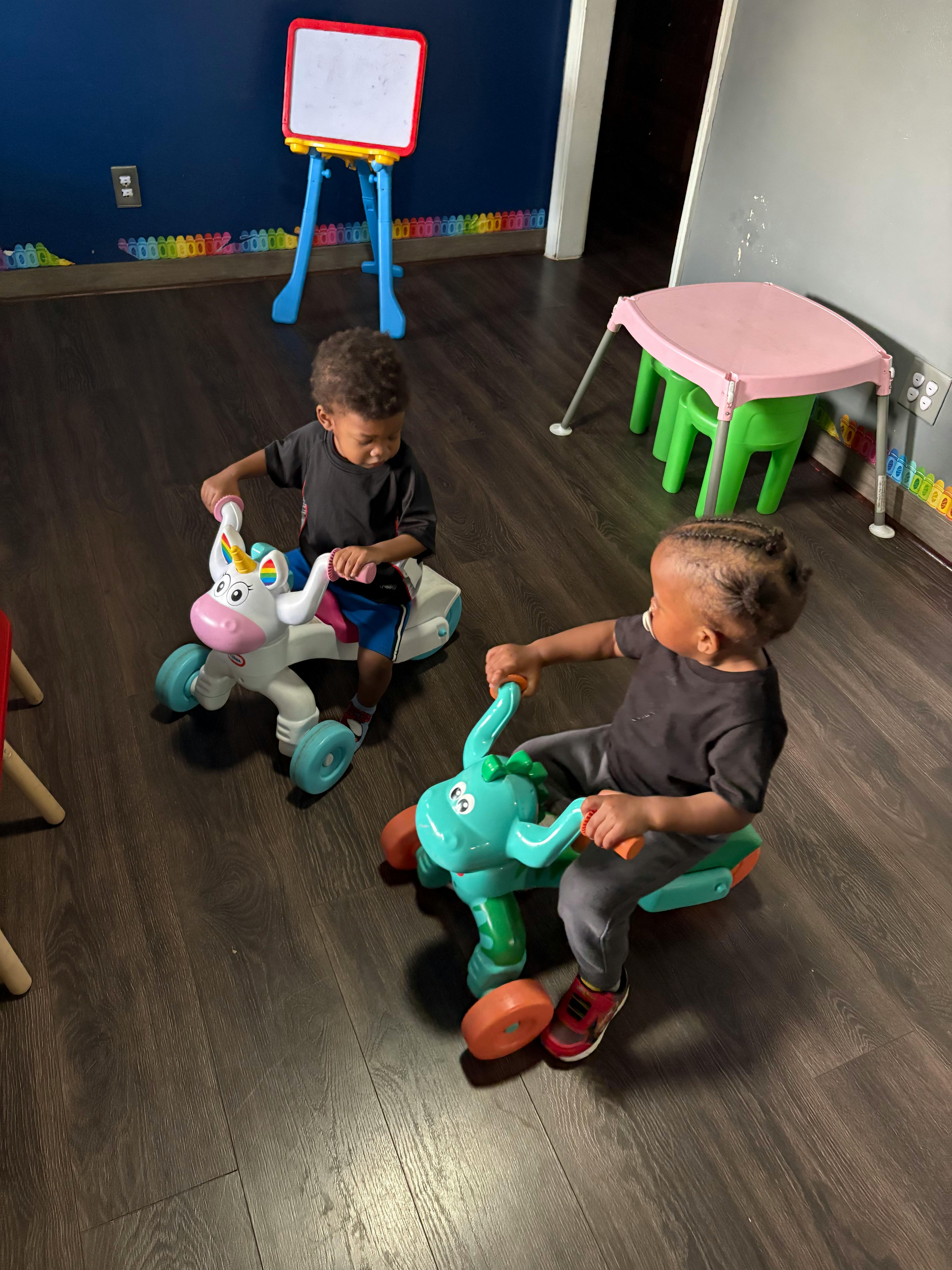 Two children riding toy vehicles indoors