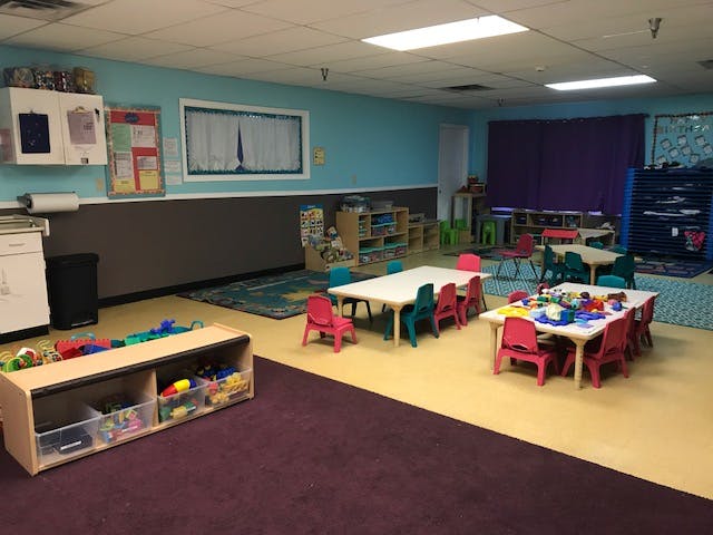 Classroom with small tables and chairs, and toy storage