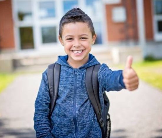 Child with backpack giving a thumbs up