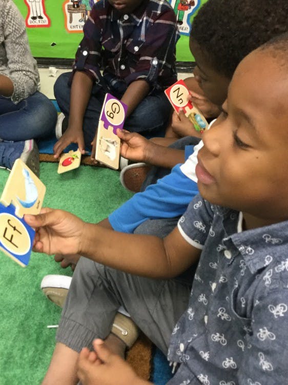 Children holding alphabet cards in a classroom
