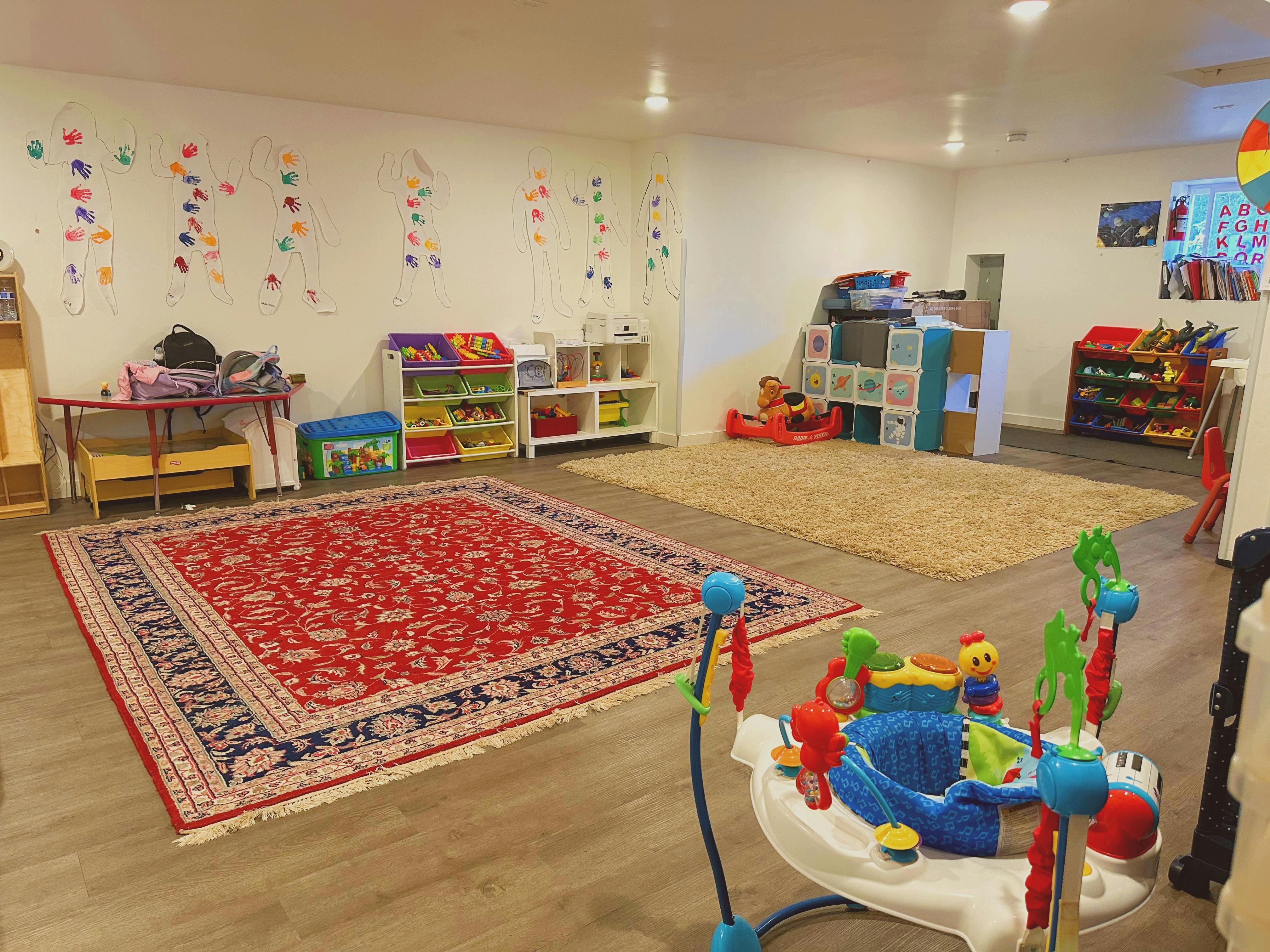 Playroom with rugs, shelves of toys, and baby activity center