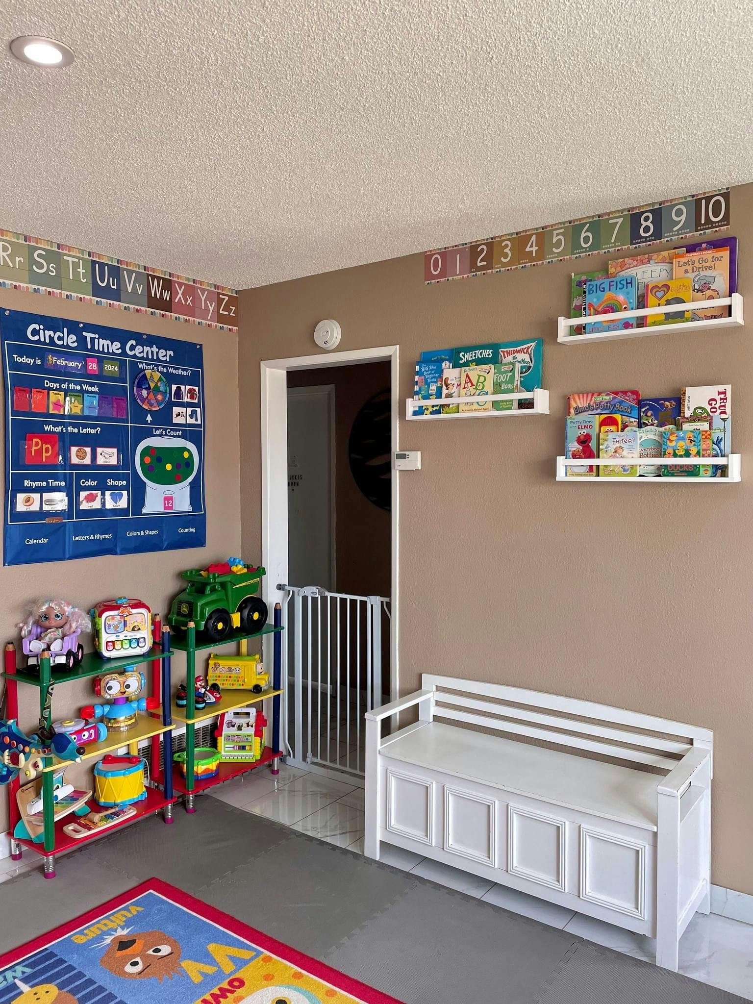 Playroom with toys, books on shelves, and a white storage bench