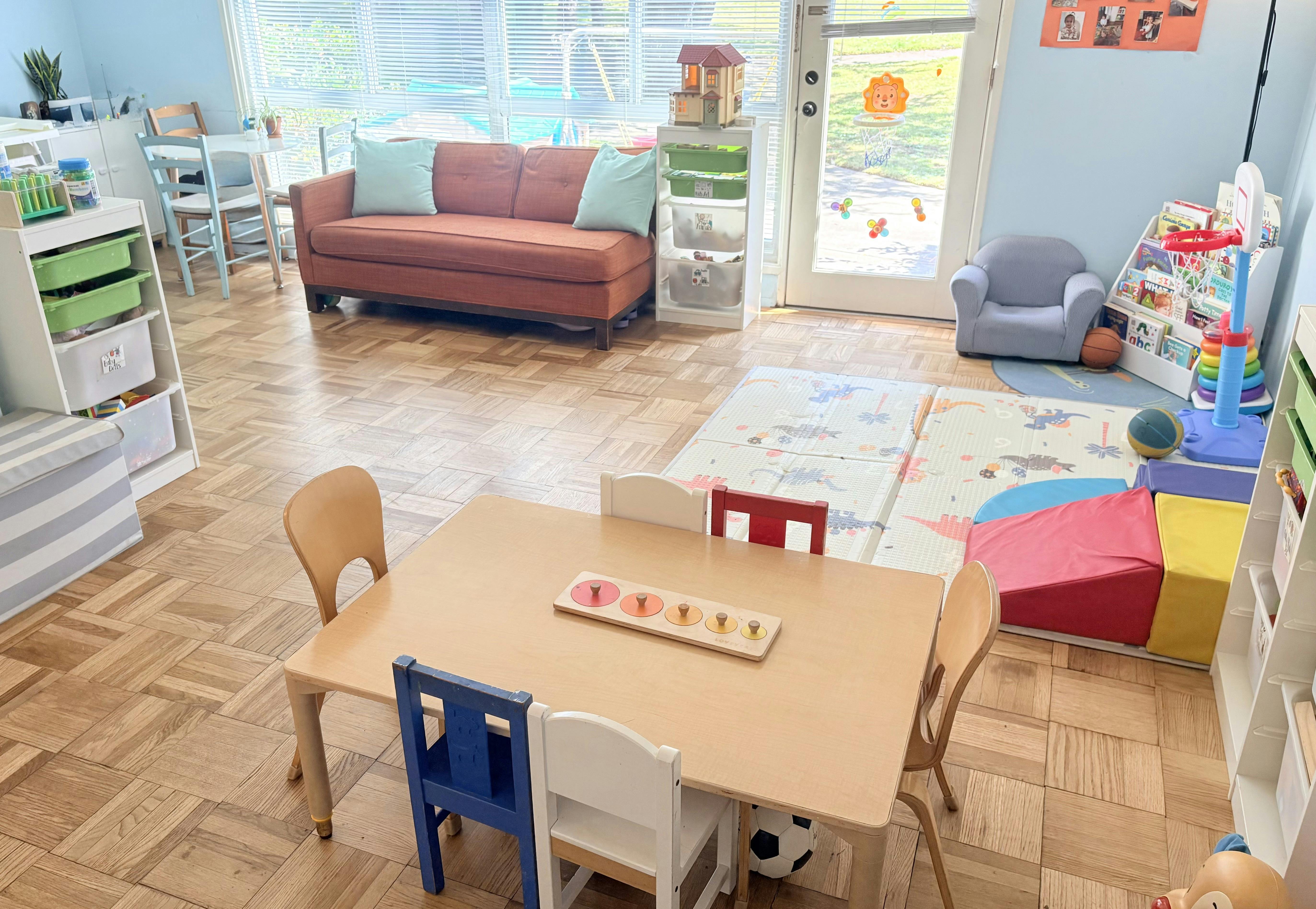 Children's playroom with a table, chairs, toys, sofa, and play mats