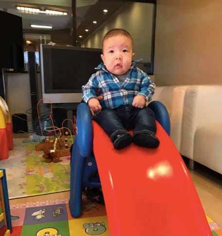 Child sitting on a red and blue slide